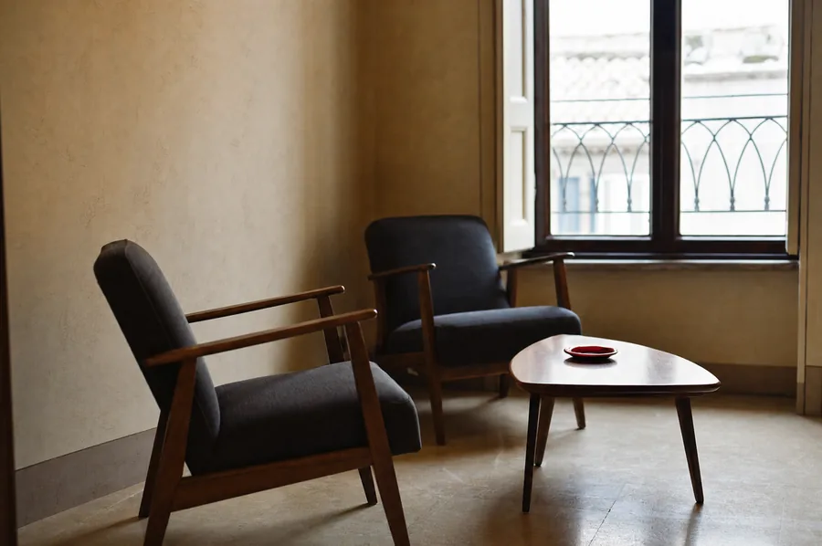 Sala d'attesa con due poltrone e un tavolino accanto a una finestra