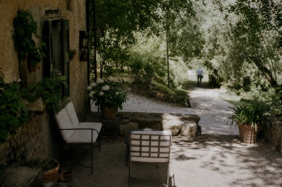 Terrazza con sedute e un vialetto ghiaiato tra gli alberi