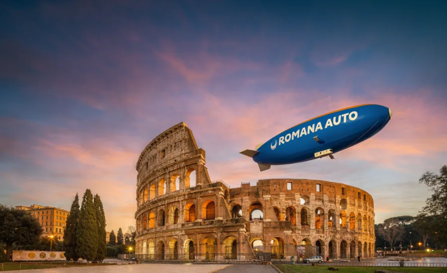 Dirigibile con il marchio Romana Auto sopra il Colosseo al tramonto